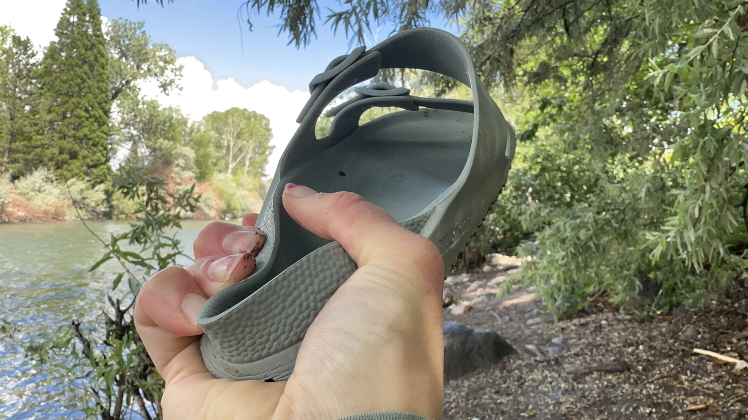 A woman holds up a sandal to show how weak the heel is when squeezed.