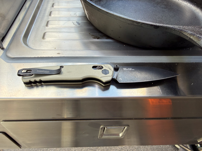 Kershaw Bel Air open on a stainless steel camp kitchen counter beside a cast iron skillet.