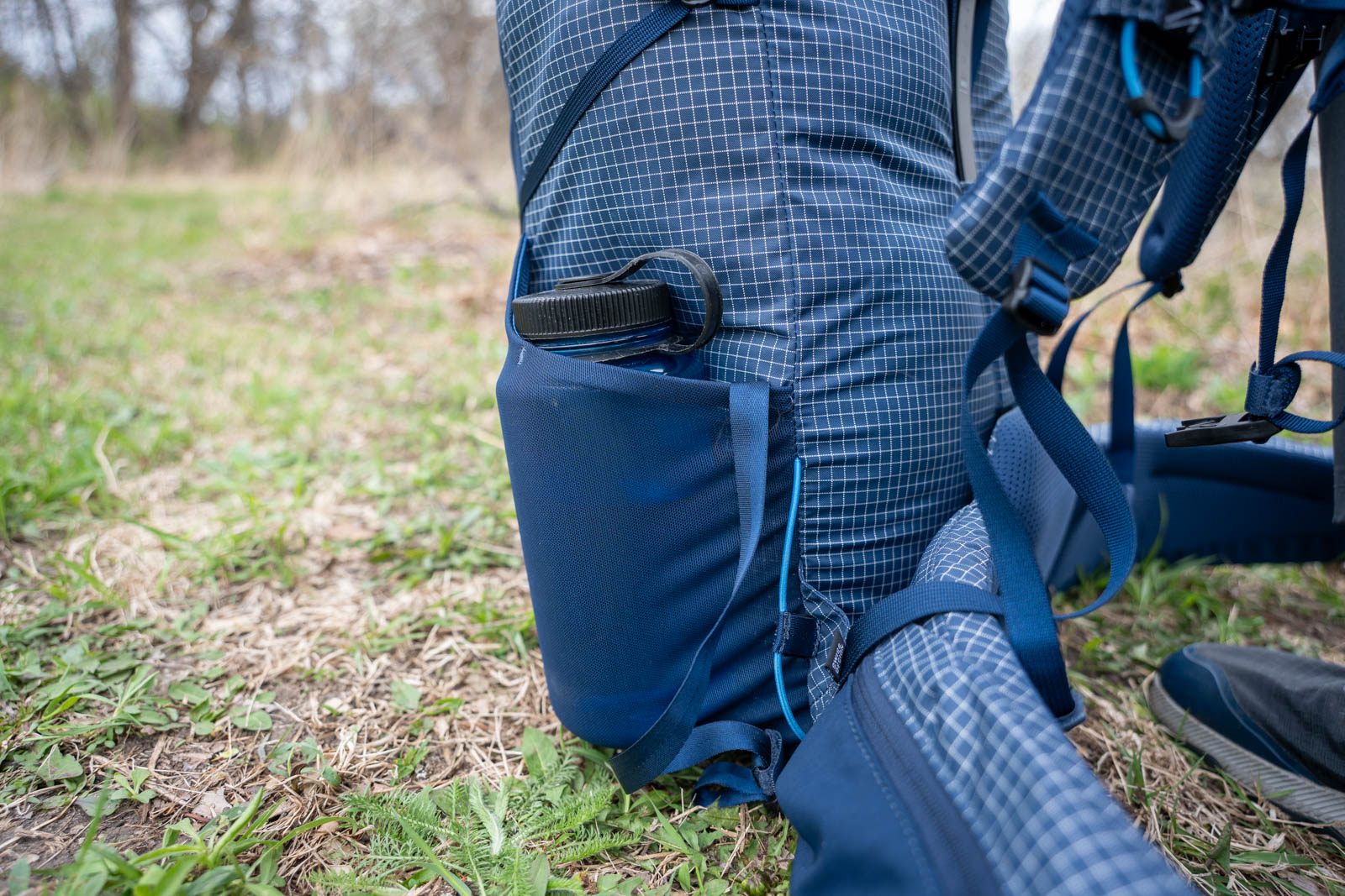 Una botella de agua en un bolsillo lateral de malla en una mochila.
