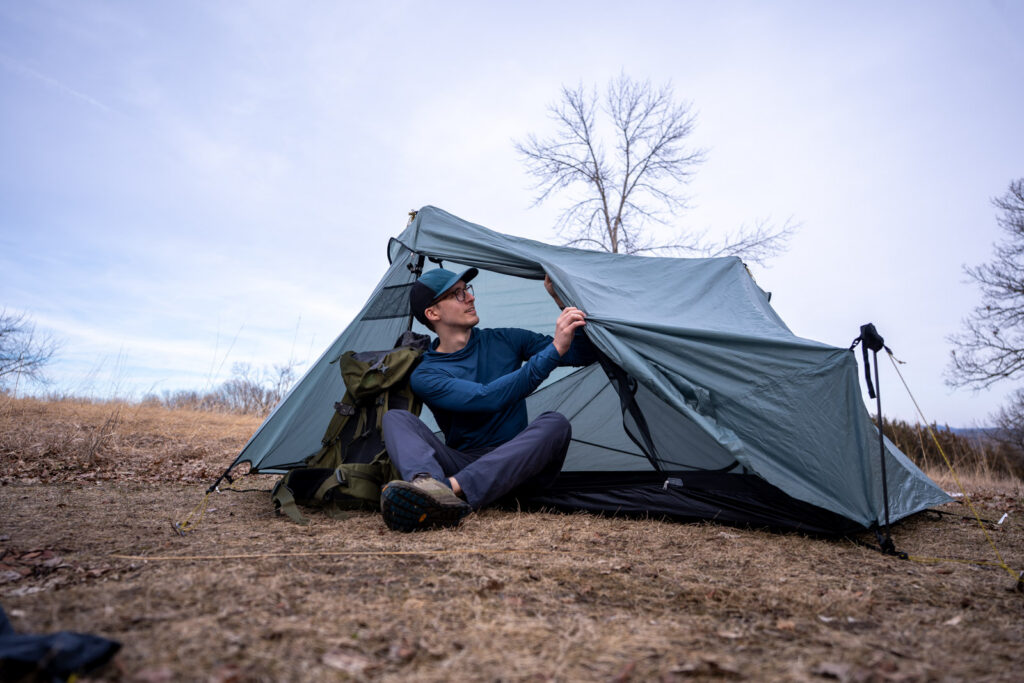 A man sits in a tent and adjusts the doors