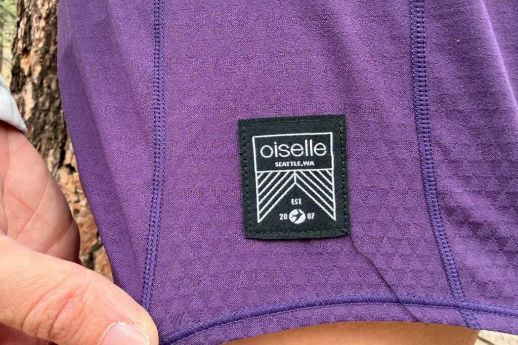 Close-up image of the Oiselle logo on a pair of hiking shorts, with one of the seams at the corner starting to come undone.