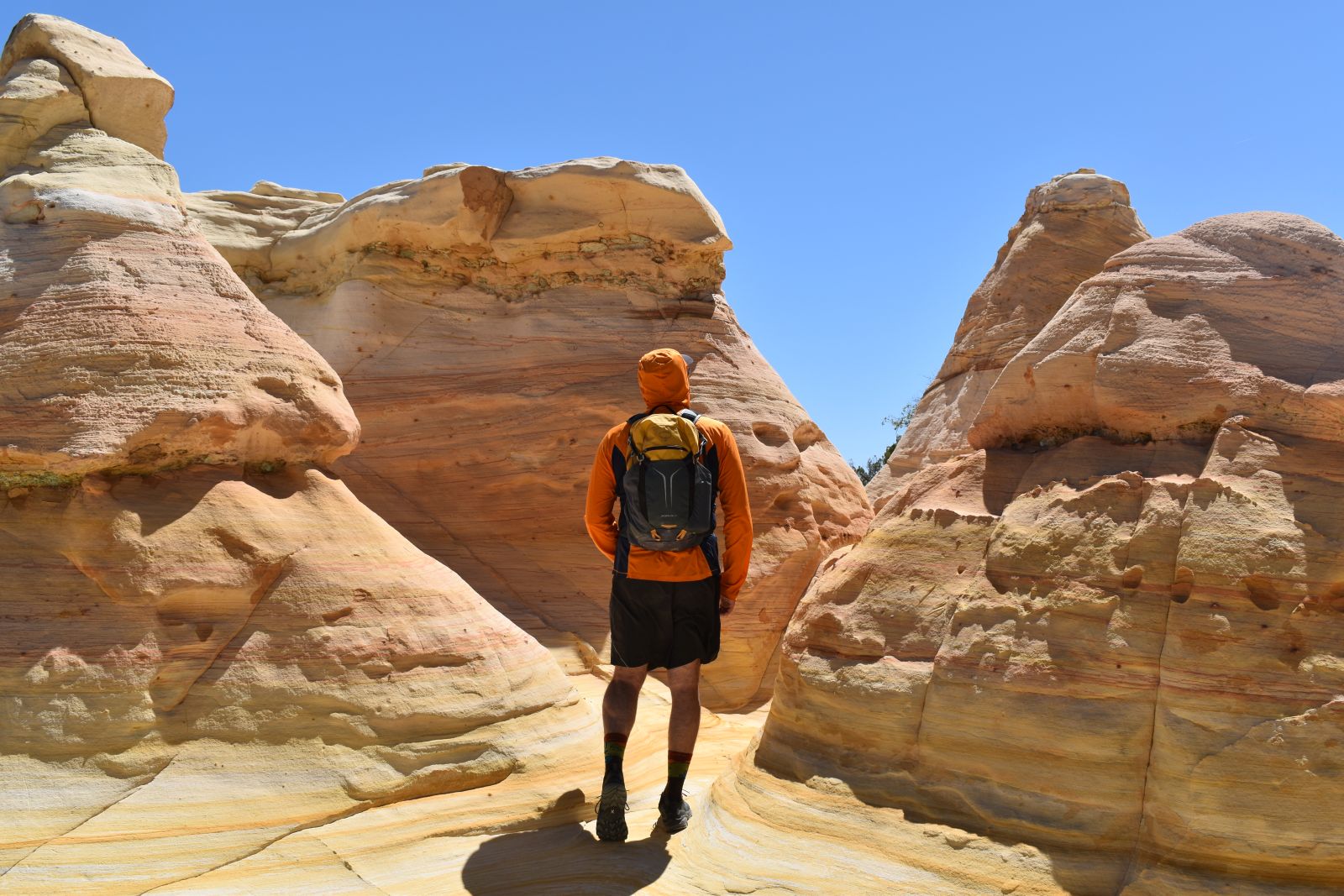 A hiker walks through hoodoos while wearing the Osprey Sportlite 20 daypack.