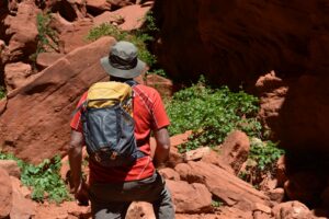 Our gear analyst hiking through a redrock slot canyon with the Osprey Sportlite 20 on his back.