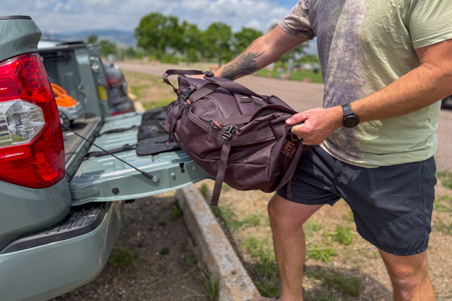 Person lifting the REI Co-op Big Haul 60 into the back of a pickup truck.
