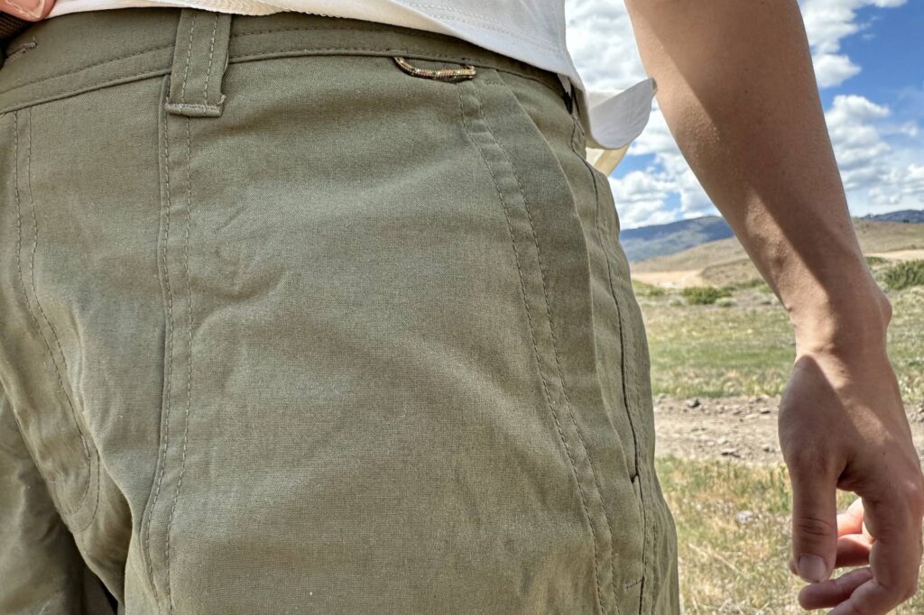 Imagen de primer plano de las costuras de un par de pantalones cortos de senderismo verdes.