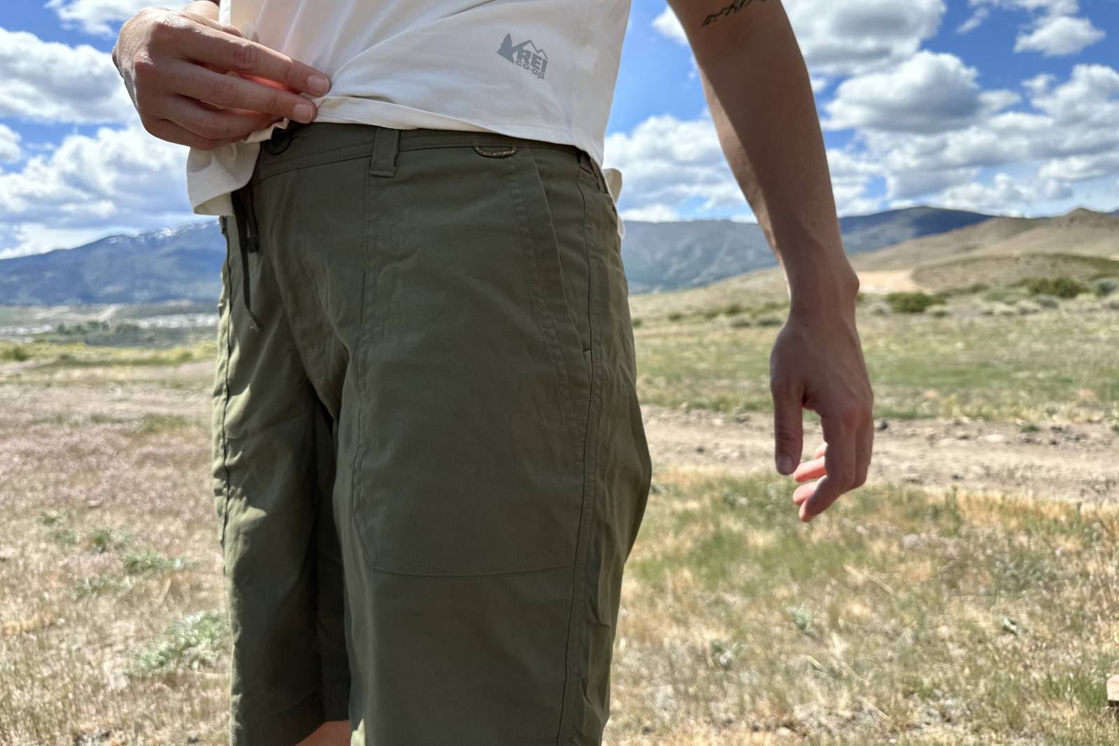 Imagen en primer plano de los detalles de un par de pantalones cortos de senderismo verdes, incluidas las costuras laterales y un bolsillo para la mano.
