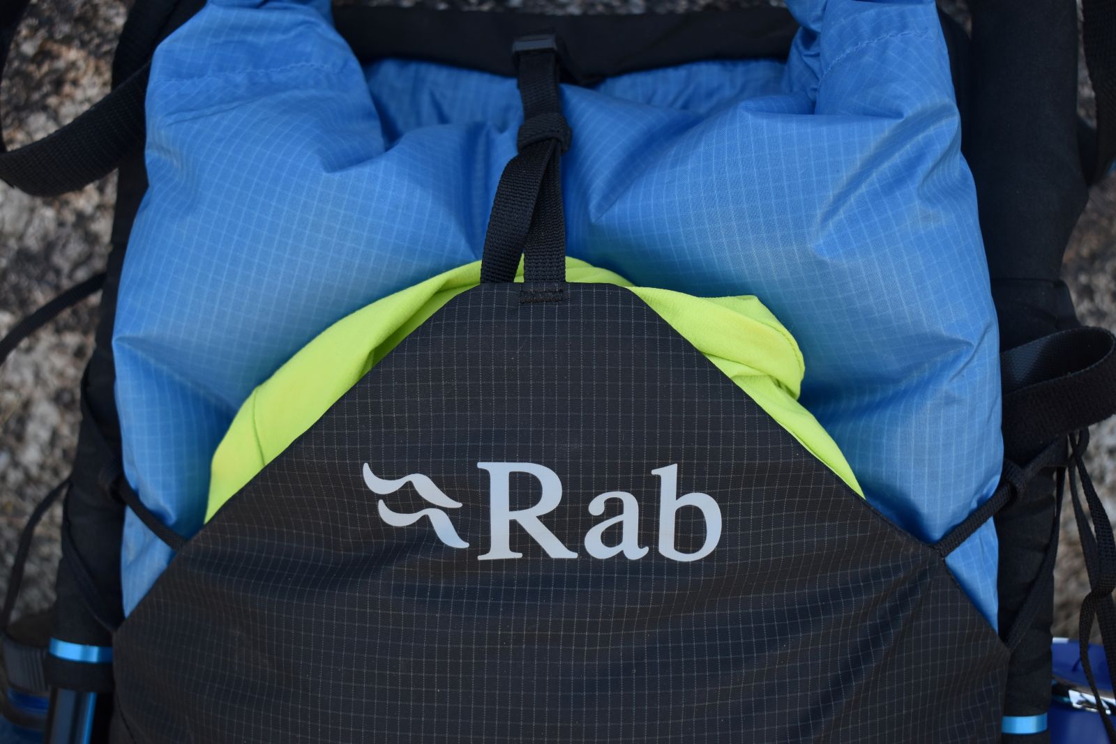 A jacket is visible in the external front pocket of the Rab Syclon XP daypack
