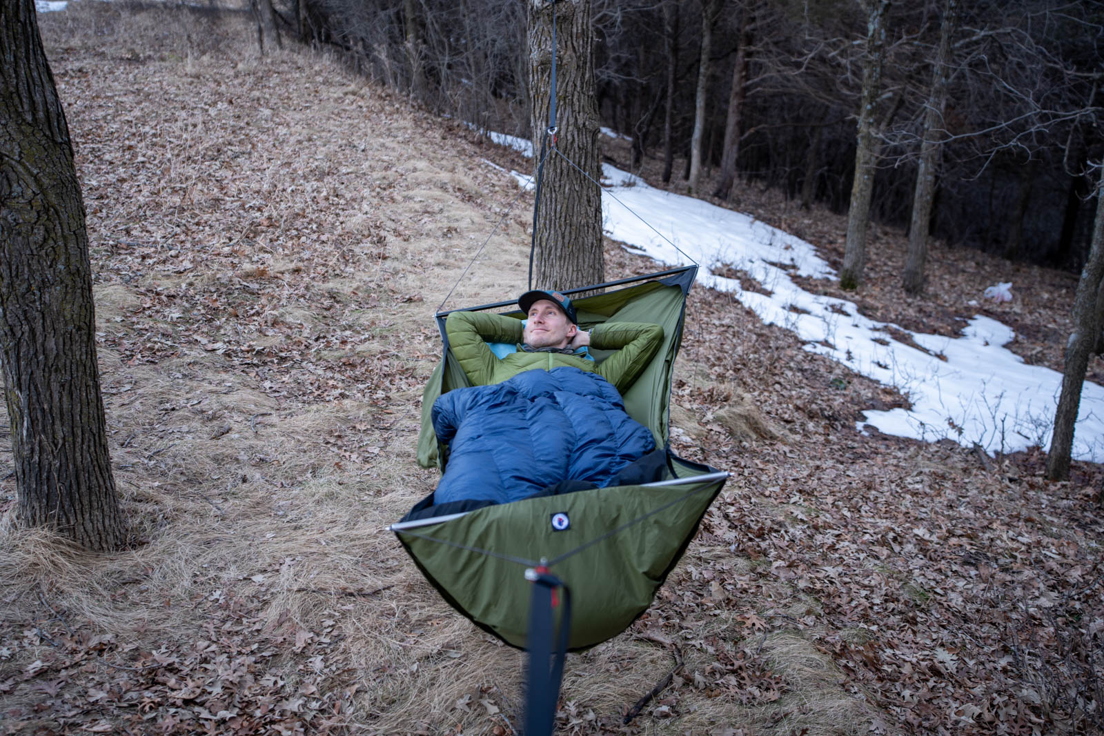 A man lies in a hammock suspended between two trees.