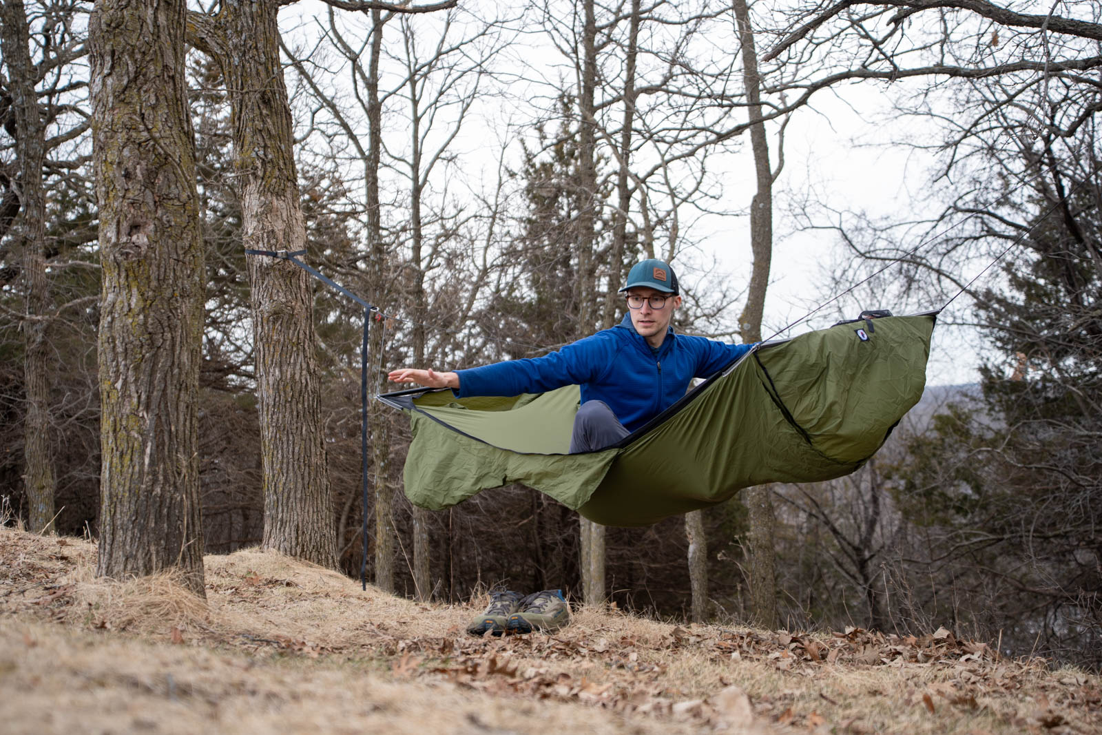 A man sits in a hammock with his arms outstretched.