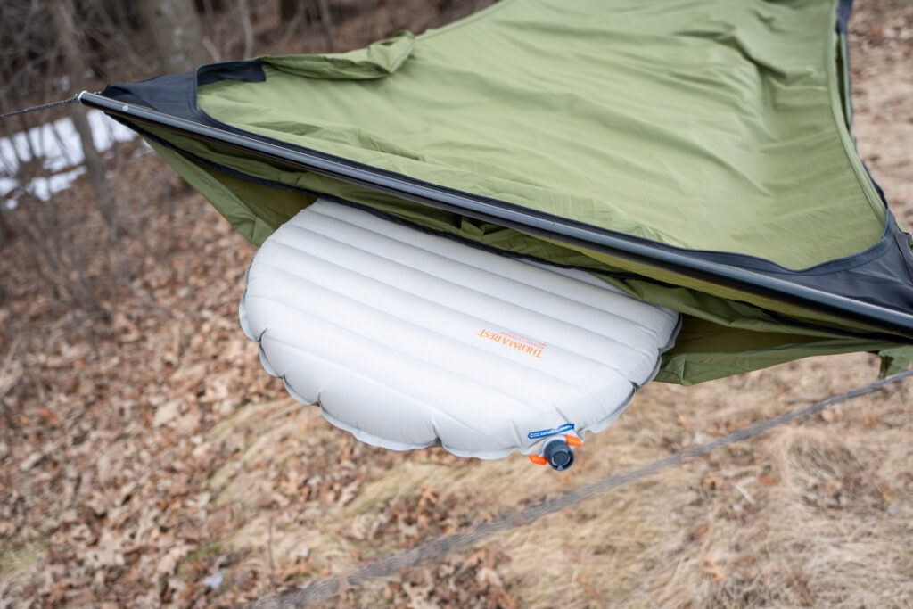 A sleeping pad peeks out of a sleeping pad compartment in a hammock.