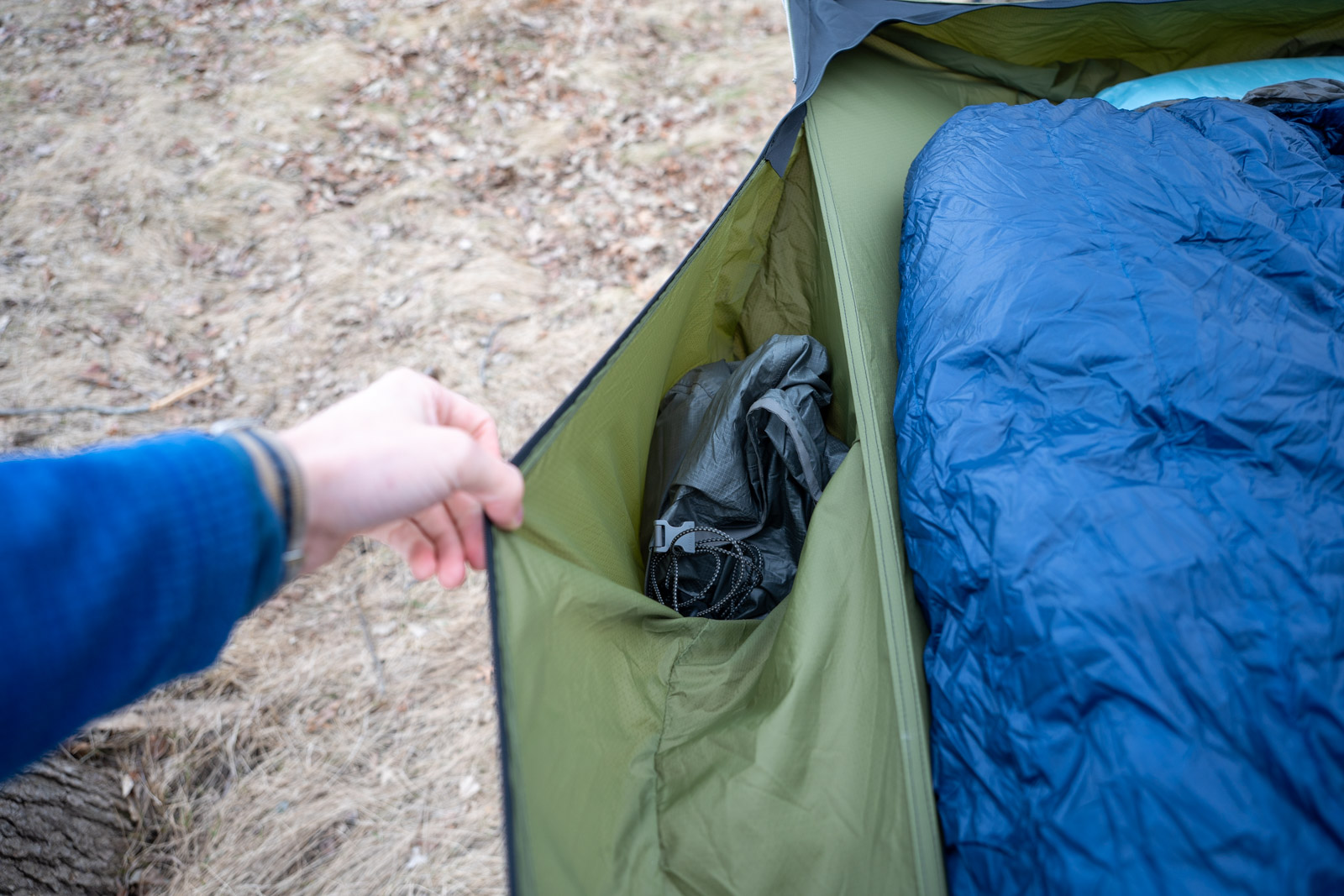A hand holds a pocket on a hammock open.