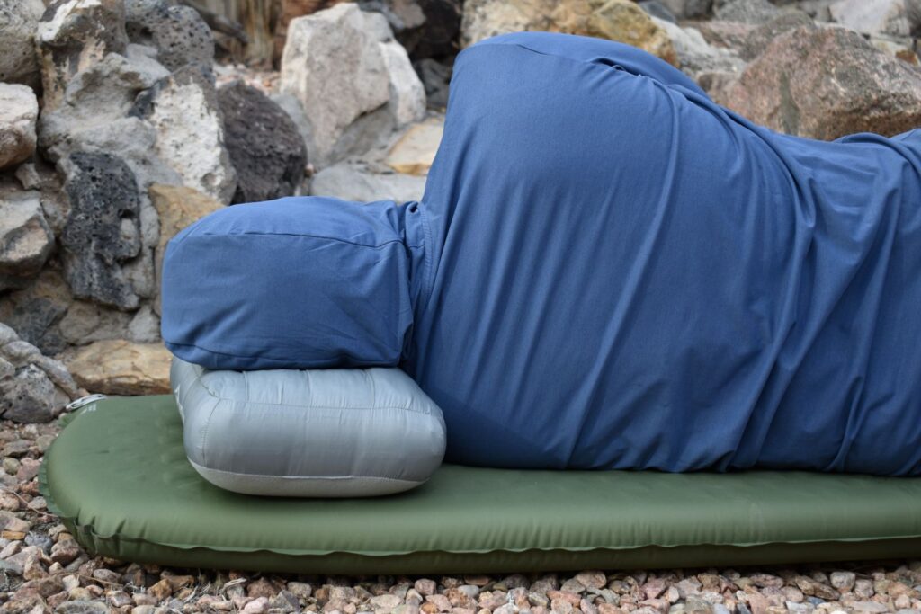 Our tester in a hood faces away from the camera while laying on his side on the Camp Plus sleeping pad