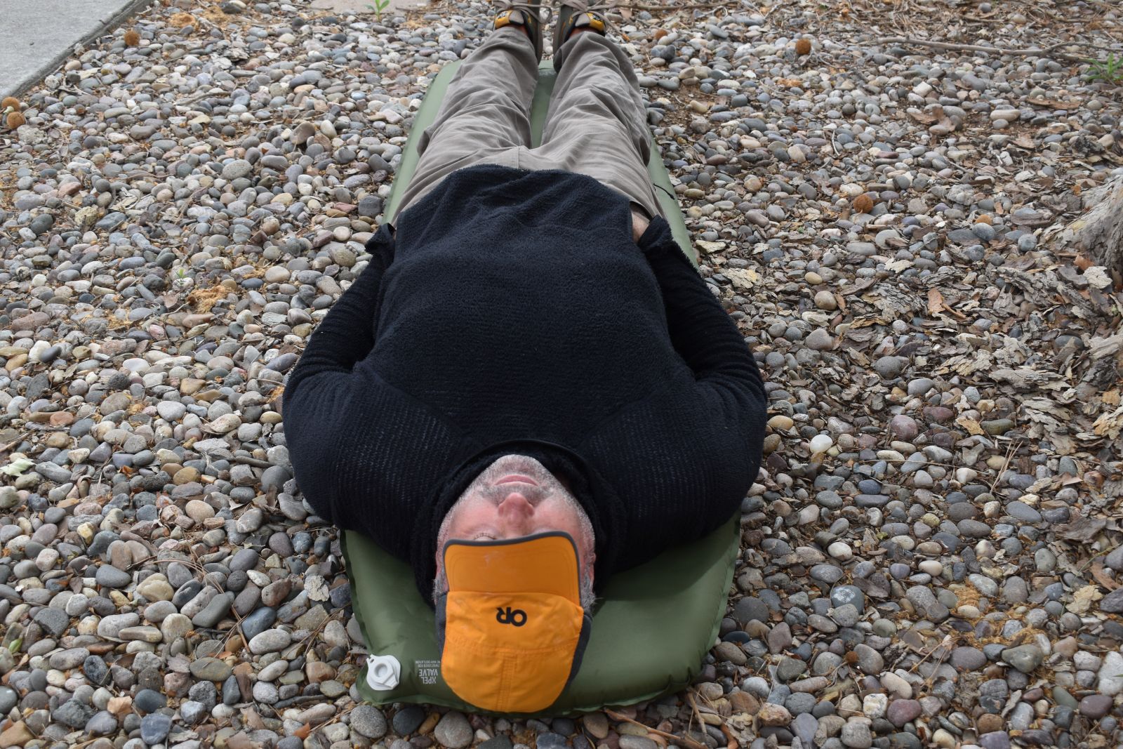 Our tester lays on the Camp Plus mattress with his elbows hanging off the edges and feet and head barely fitting on the mattress