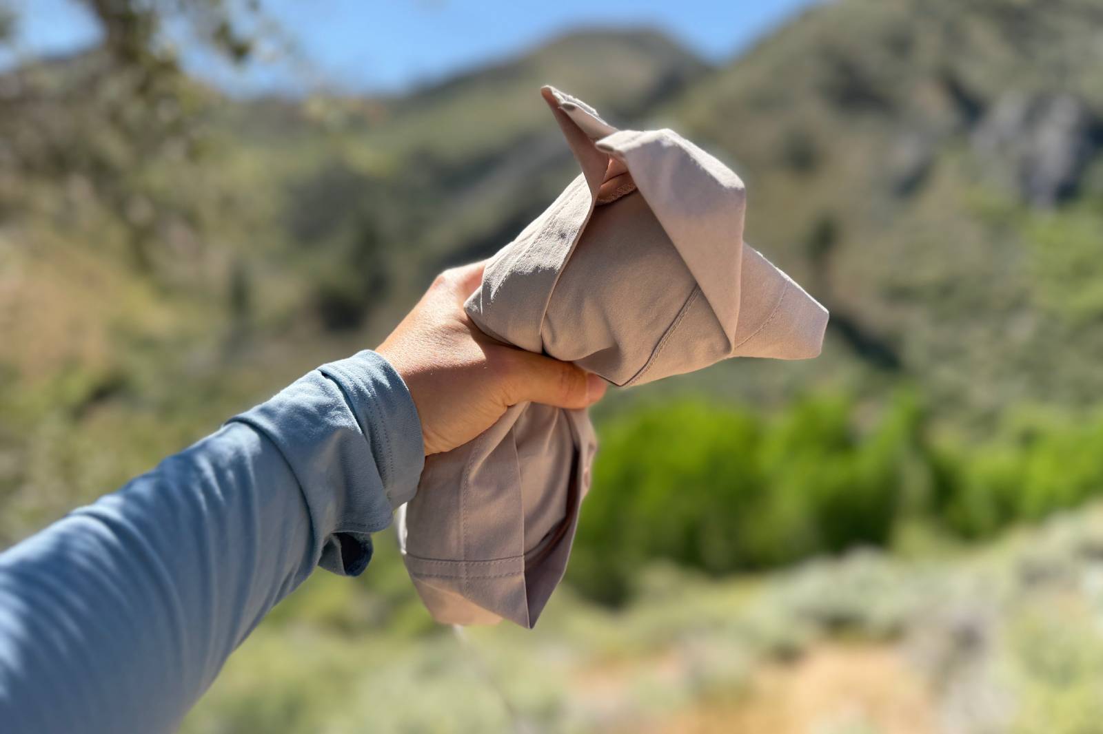 Close-up image of a woman holding a pair of beige, rolled-up hiking shorts.