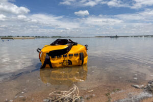 Yellow The North Face Base Camp Waterproof Duffel 50L sitting partially in shallow lake water.