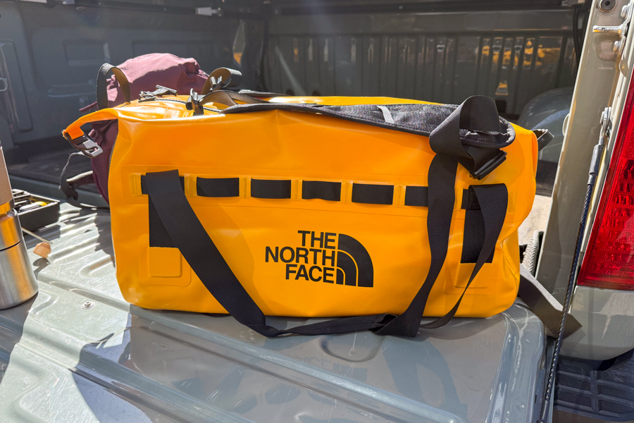 Yellow The North Face Base Camp Waterproof Duffel 50L sitting in the open bed of a pickup truck.
