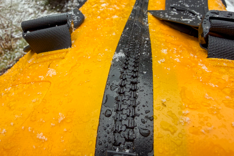Close-up of the waterproof zipper on The North Face Base Camp Waterproof Duffel 50L with snow and water droplets on the fabric.