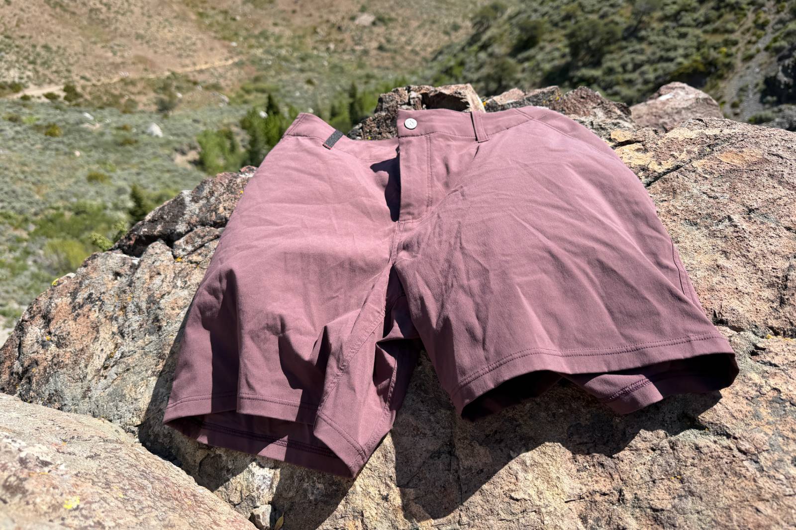 Close-up image of a pair of hiking shorts lying on a rock overlooking the trail and forest below.