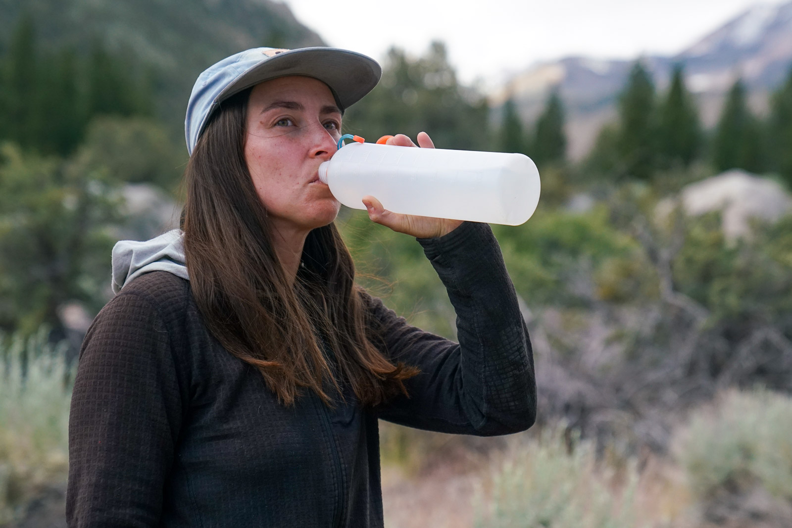 A close up of a person drinking from a water bottle.