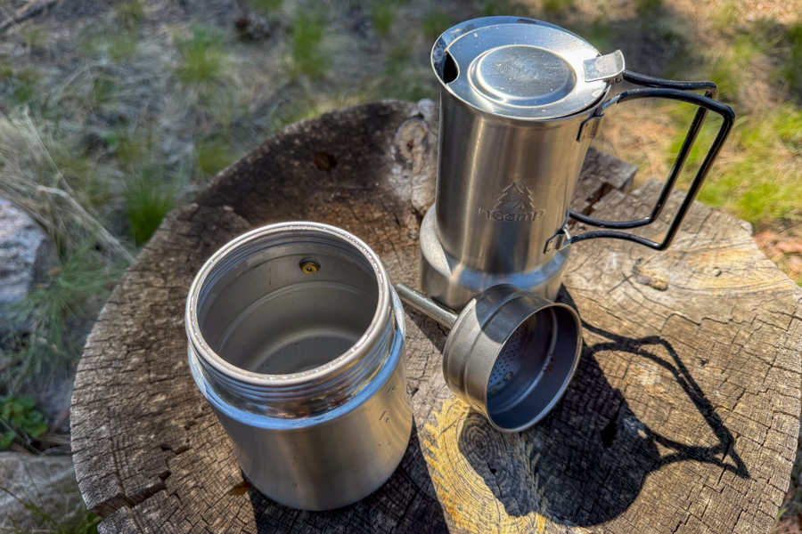 A coffee maker opened up to show the water chamber, filter basket, and upper brew section before assembly.