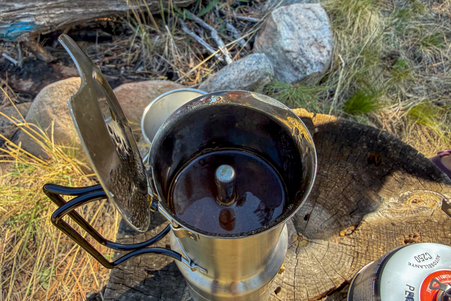 Top-down view into the upper chamber of a coffee maker showing freshly brewed espresso inside the stainless steel pot.