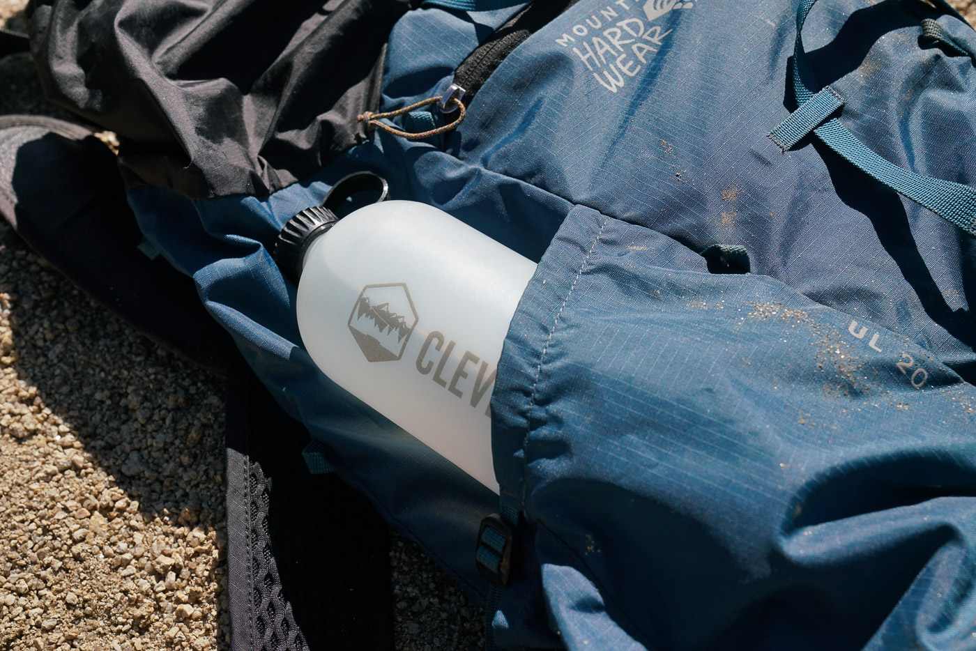 A close up of a water bottle poking out of the pocket of a pack.