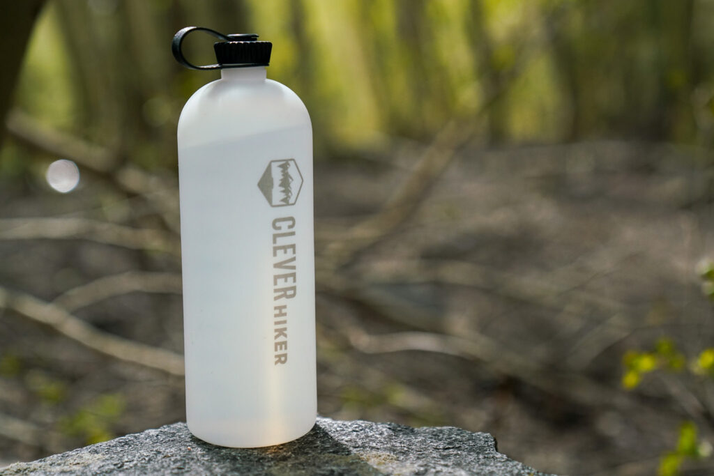 A water bottle sits on a rock with a forest in the background.