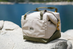 A close up of a soft-sided cooler sitting on a rock.
