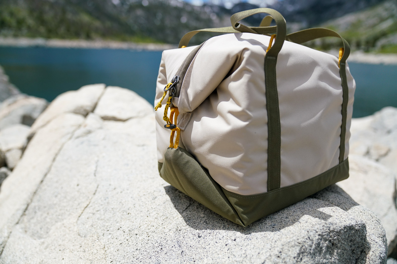 A close up of a soft-sided cooler sitting on a rock.