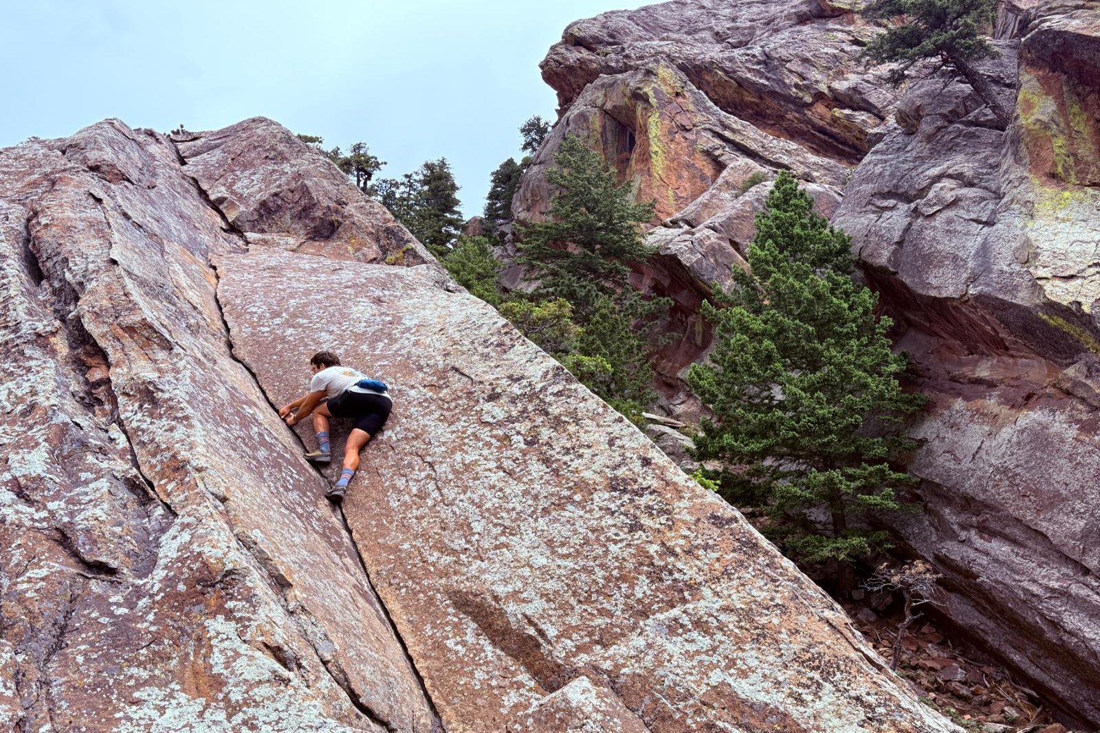 Ascending a 5th class dihedral in Boulder's Flatirons while wearing a blue fanny pack.