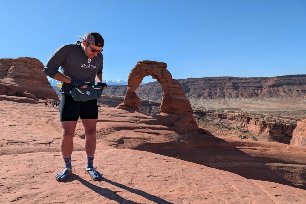 Searching for some sunscreen in the Black Diamond Pursuit 6 with Delicate Arch in the background.