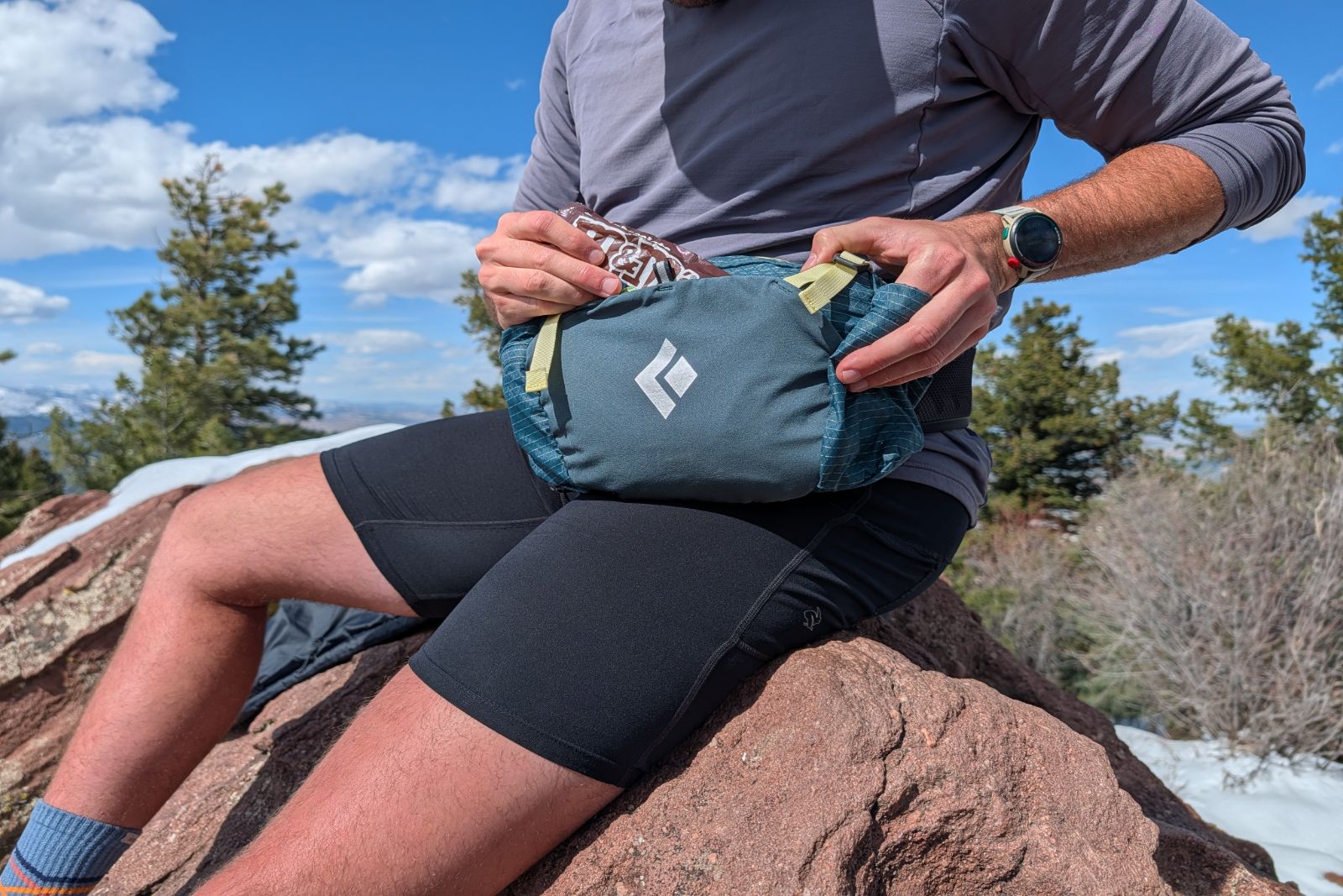 Close-up of a hiker reaching for snacks stashed inside a blue lumbar pack.