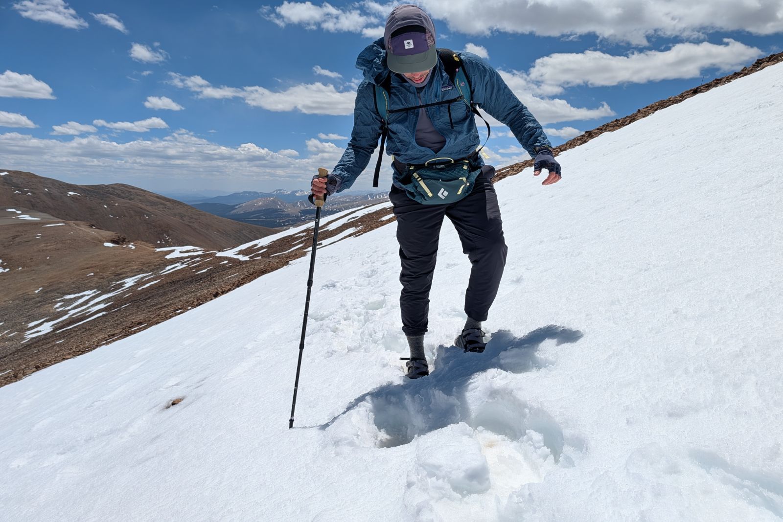 Traversing a low-angle snow slope while wearing a blue lumbar pack.
