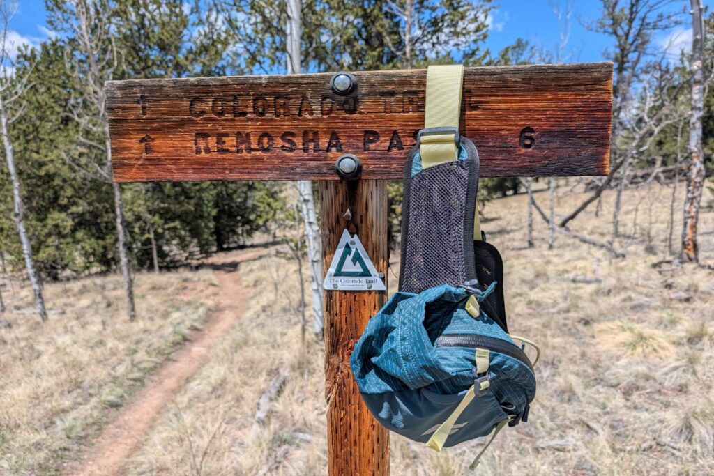 A blue lumbar pack hangs off of a Colorado Trail junction sign.