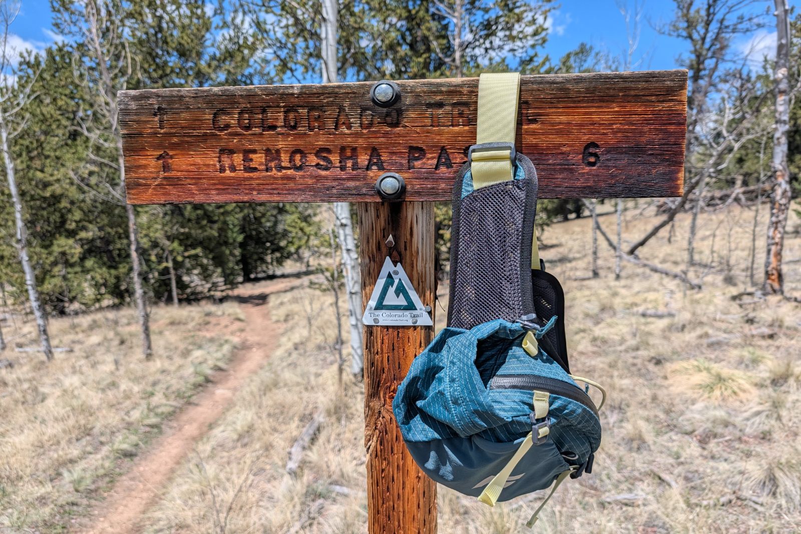 A blue lumbar pack hangs off of a Colorado Trail junction sign.