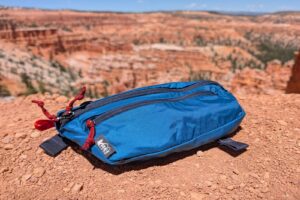 A blue fanny pack sitting on red dirt overlooking hoodoos in Bryce Canyon National Park.