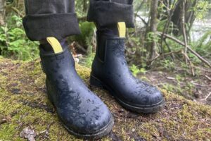 Close up of navy ankle rain boots standing on a moss-covered log