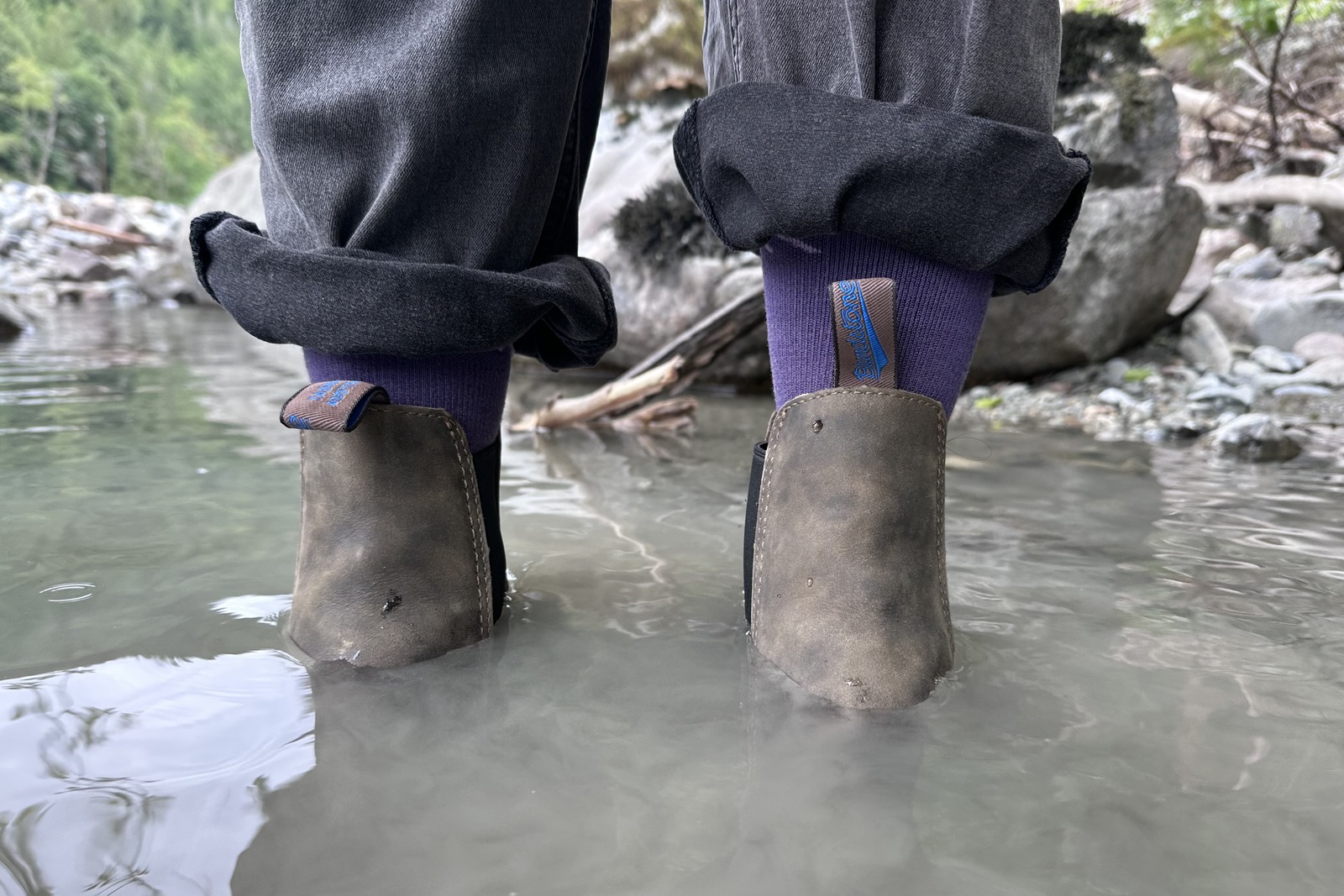 Close-up of leather ankle boots standing ankle deep in a river.