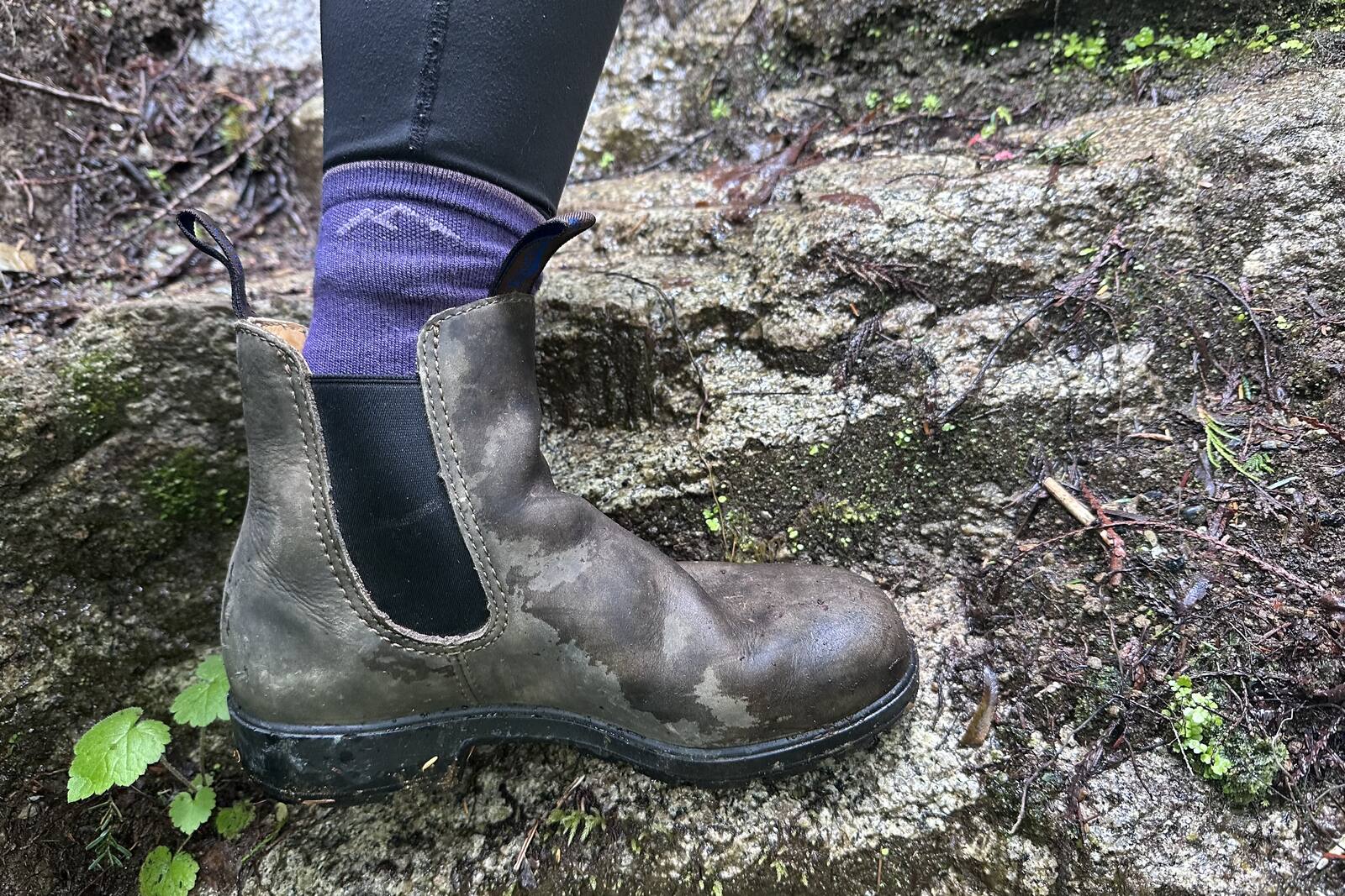Close up of a leather ankle boot stepping on wet rock.