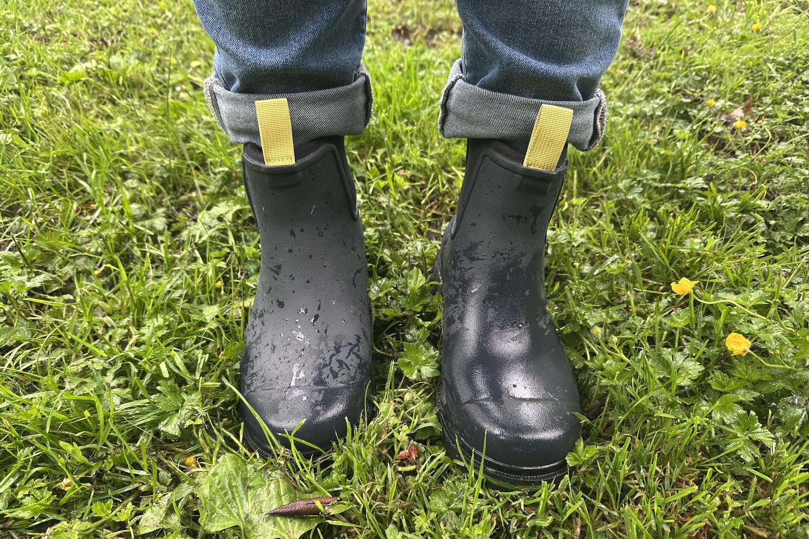 Close-up of navy ankle boots standing in wet grass.