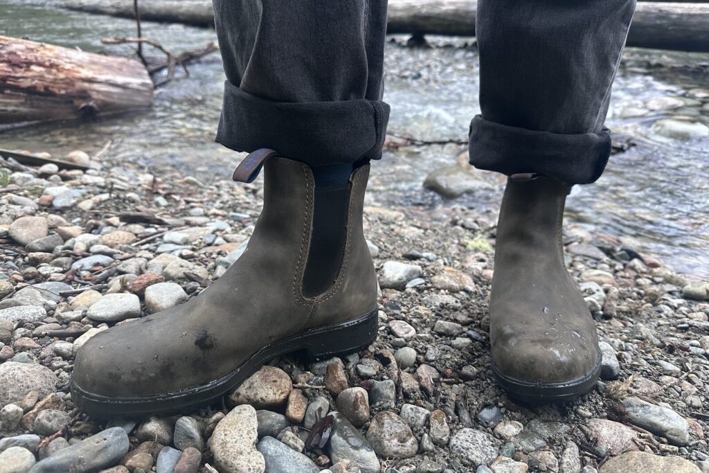 Close up of leather ankle boots standing on a gravel bar next to a river