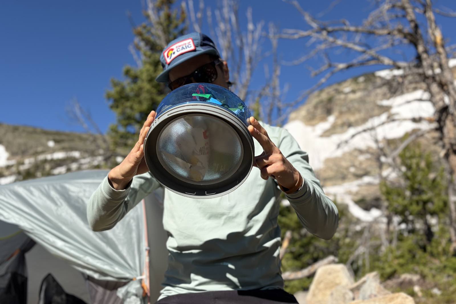A hiker holds half of a bear canister up to show its silicone divider.