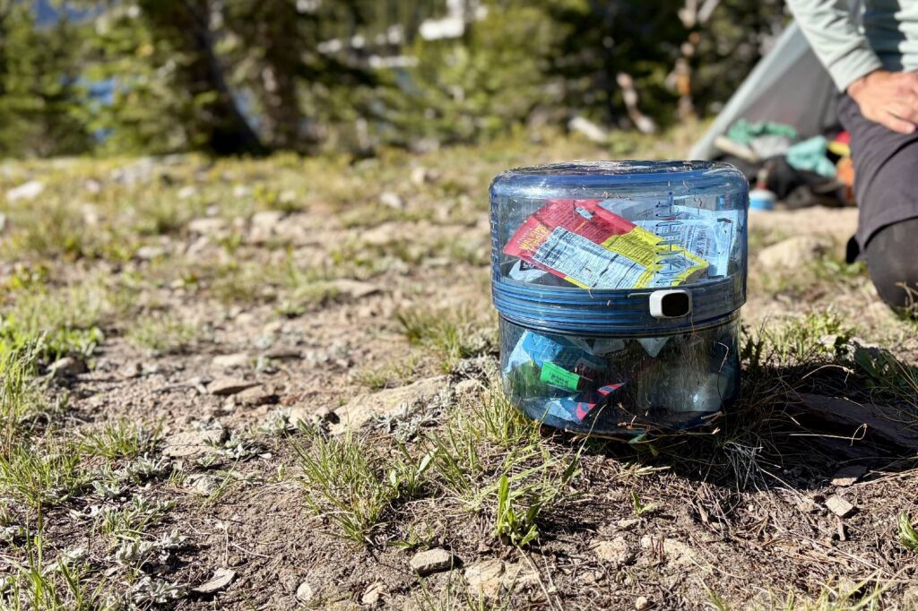 A clear blue bear canister with food inside.