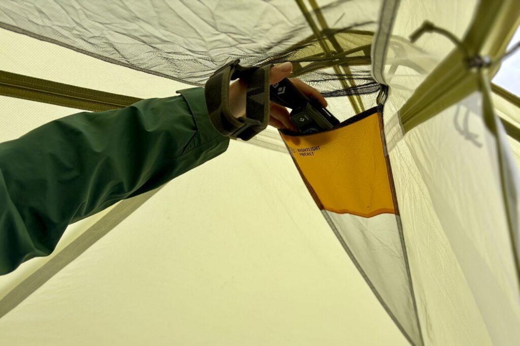 a hiker stashes a headlamp in an overhead nightlight pocket