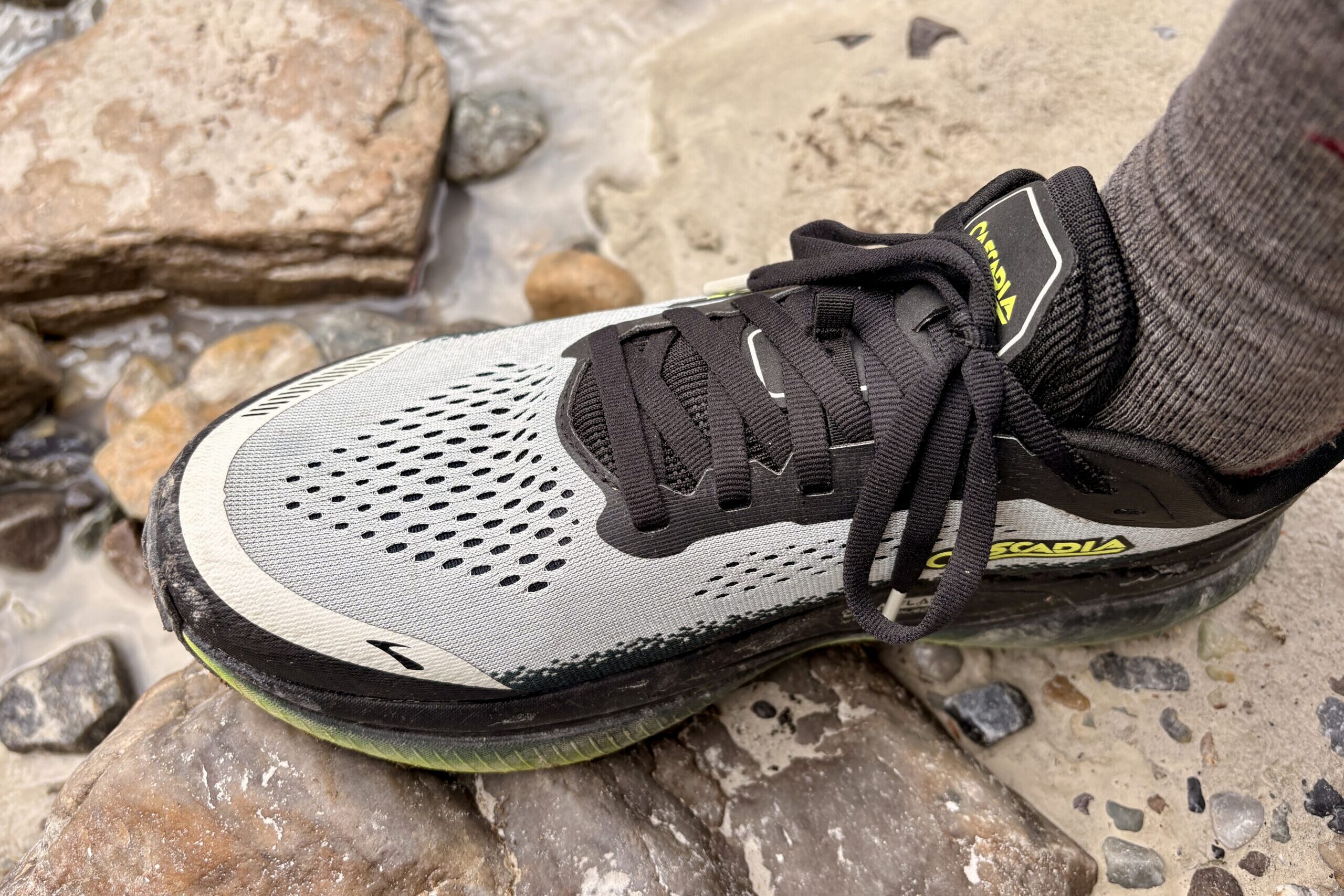 A closeup of a grey and black men's running shoe on a rock
