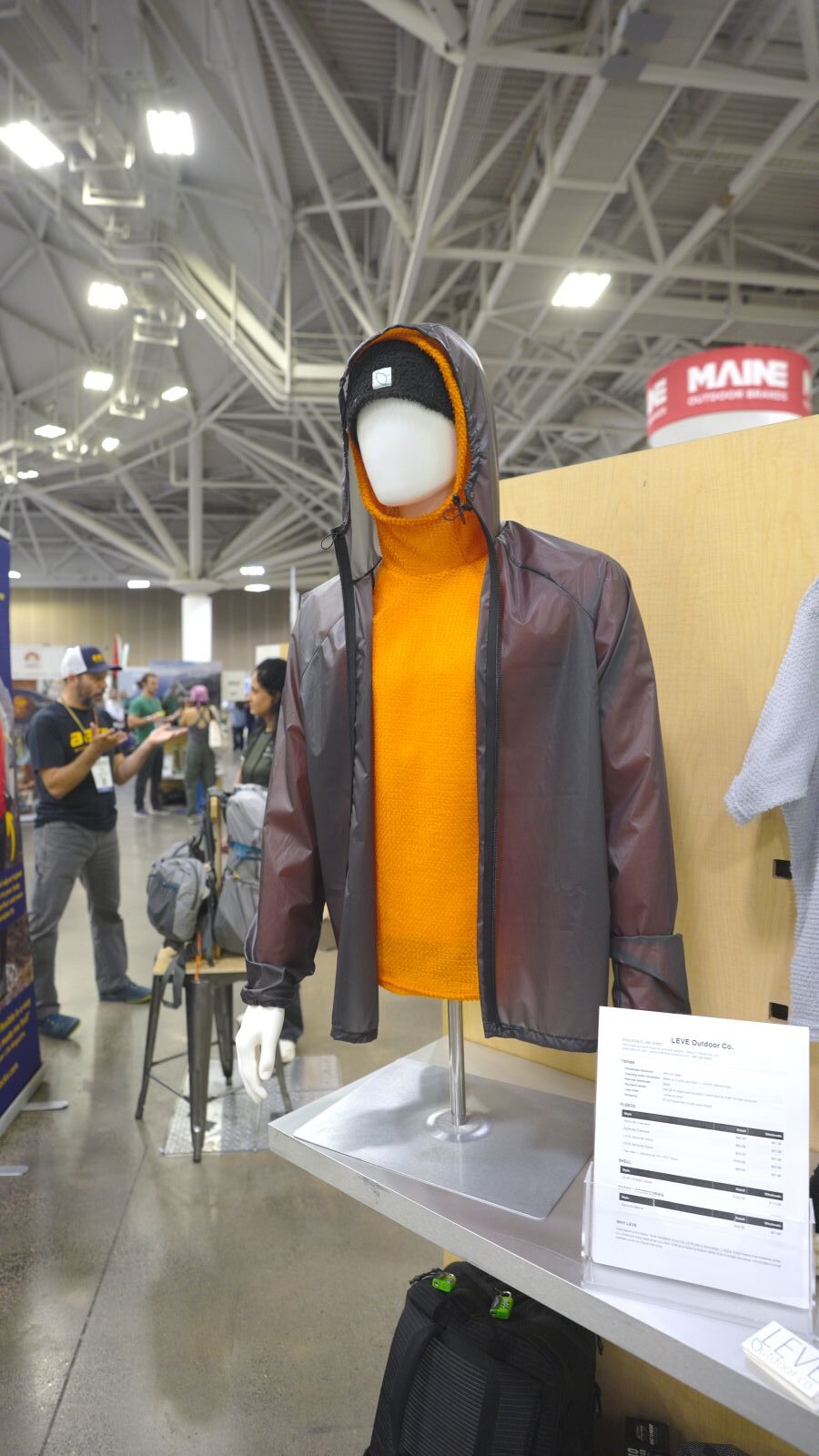 A grey rain jacket on a mannequin at a trade show.