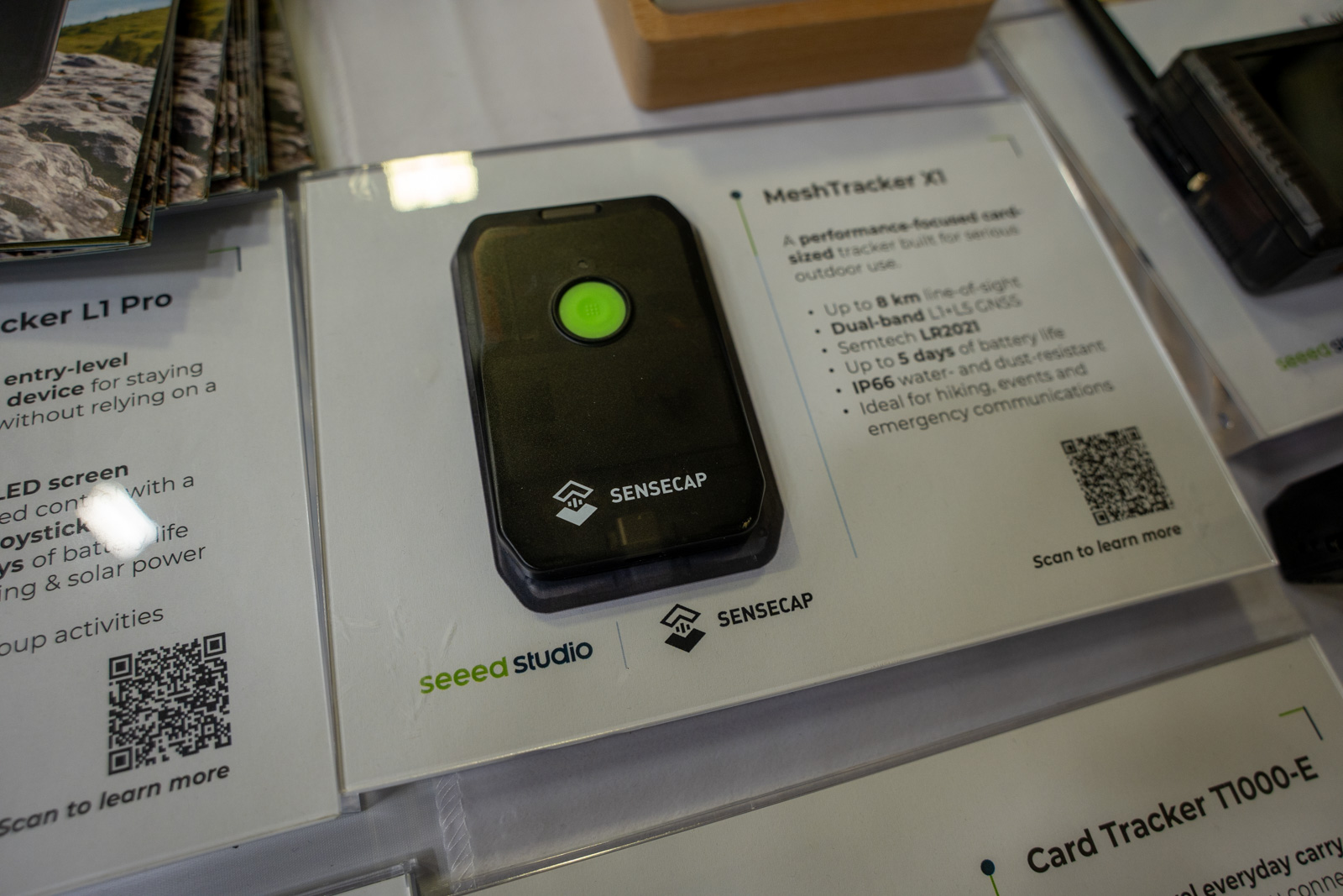 A black credit card sized device with a green button on a trade show display.