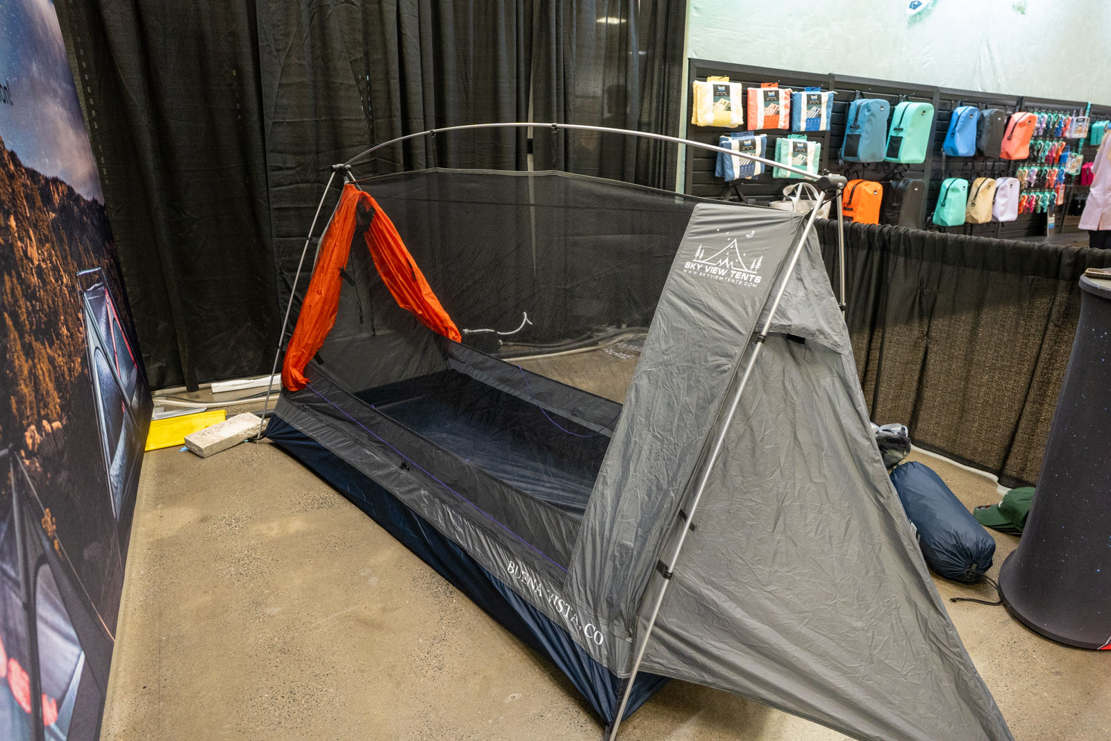 An A-frame style tent sits on a show floor with it's rain fly pulled back